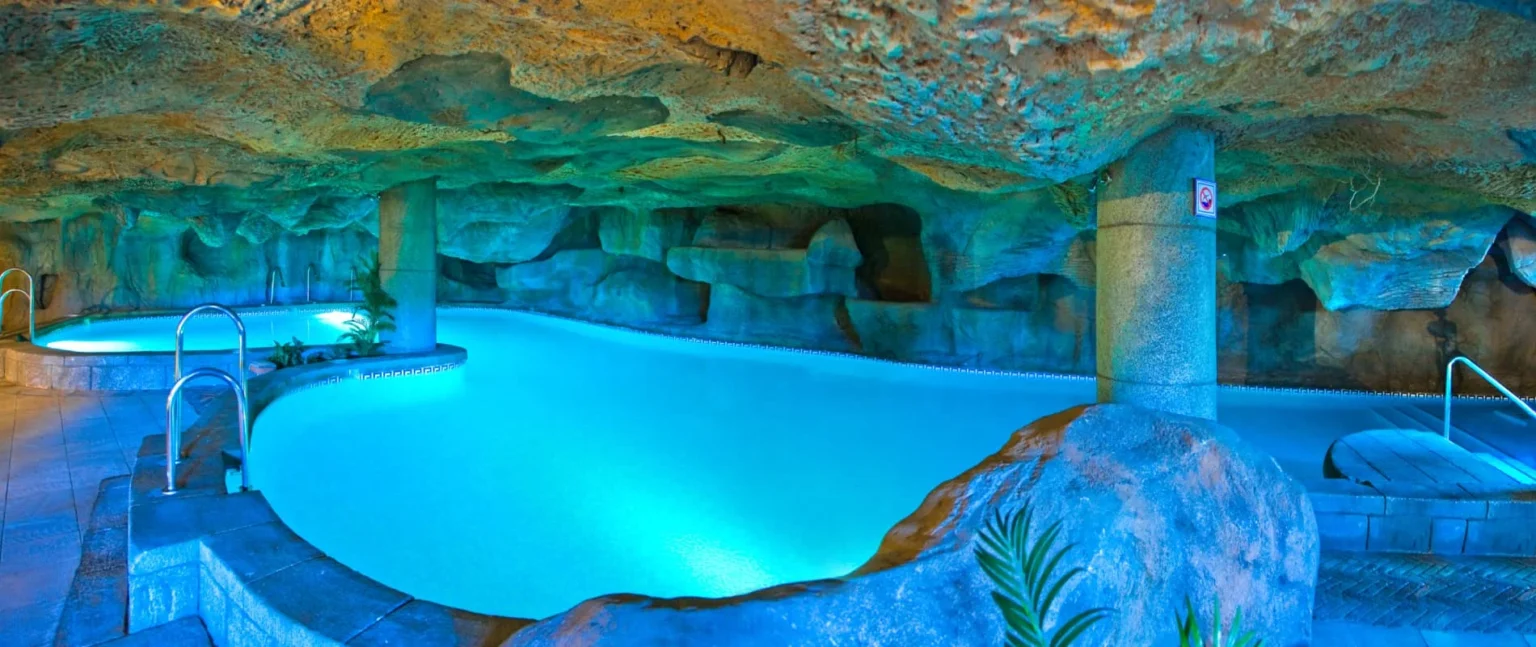 Piscina cubierta con iluminaci&oacute;n azul, bajo de piedra y gruta decorativa
