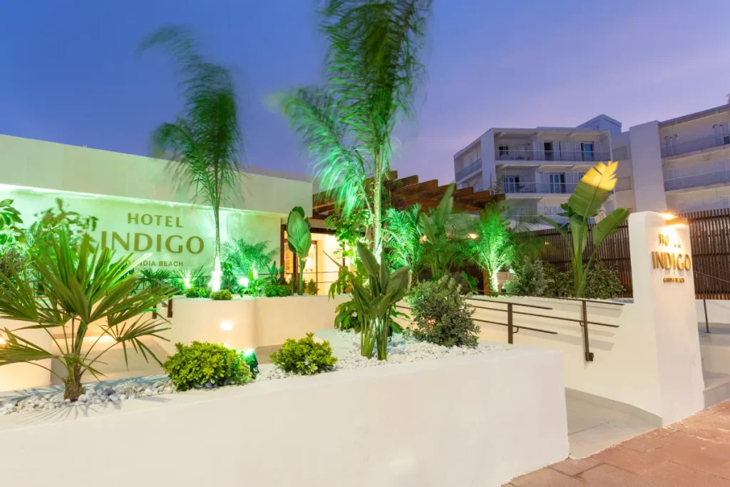 Entrada del Hotel Indigo con plantas y palmeras al atardecer