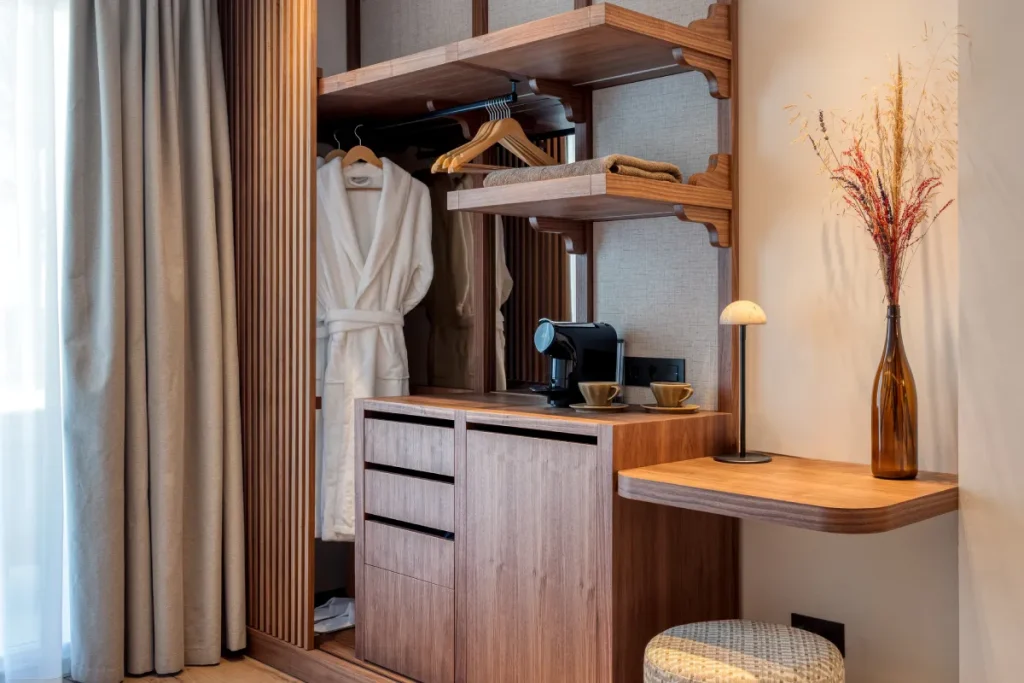 Rinc&oacute;n de vestidor con albornoz, perchas, cafetera y mesa de madera.