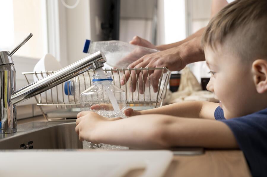 Niño feliz lavando platos ayudando a su madre 