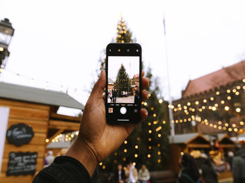 Movil haciendo una foto en un mercadillo navideño con luces de fondo
