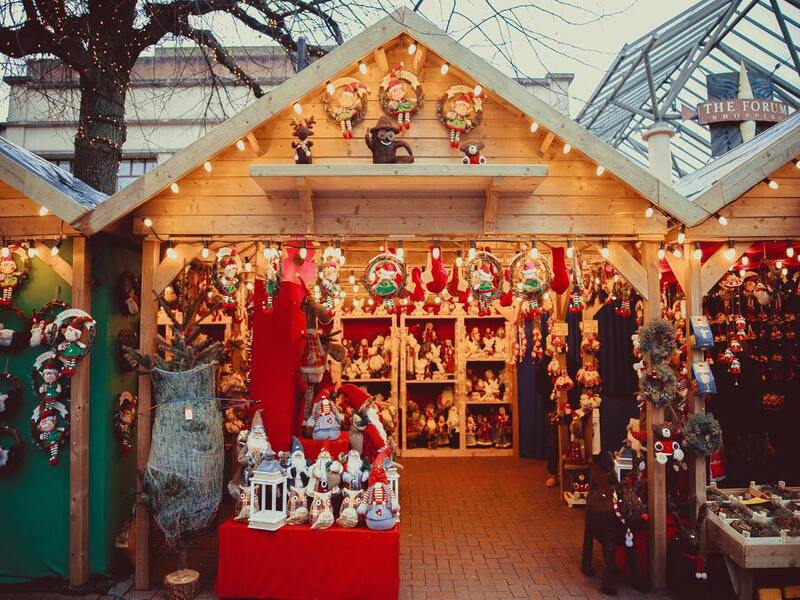 Mercadillo navideño en una caseta con productos artesanos en tonos rojos y luces de fondo.