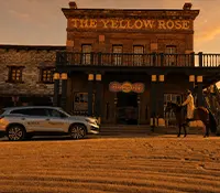 Fachada del hotel “The Yellow Rose” al atardecer, con personas y coches