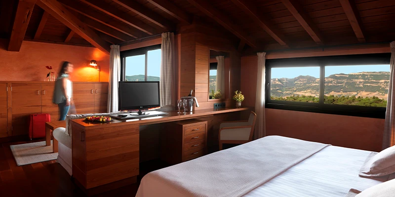 Habitaci&oacute;n acogedora de madera con vista a monta&ntilde;as por la ventana.