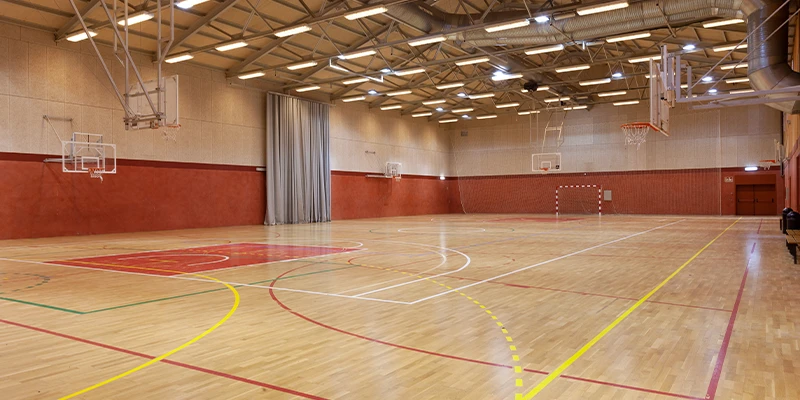 Gimnasio amplio con canchas de baloncesto y ventanales grandes.