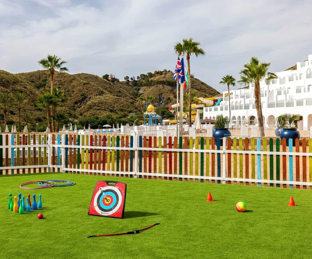 &Aacute;rea de juegos infantil en hotel, con c&eacute;sped, banderas y tocones de tiro