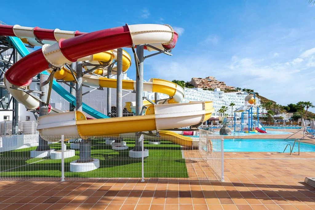 Toboganes acuáticos rojos y amarillos junto a piscinas al aire libre