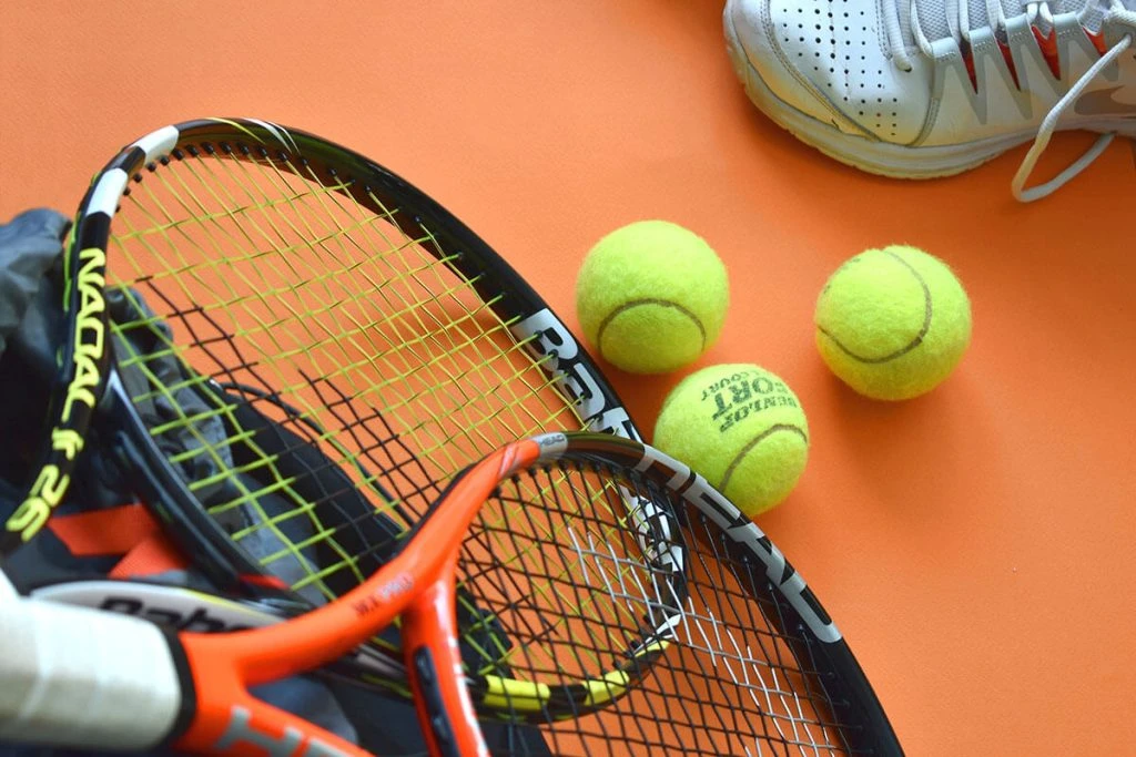 Raquetas de tenis y pelotas de tenis sobre fondo naranja