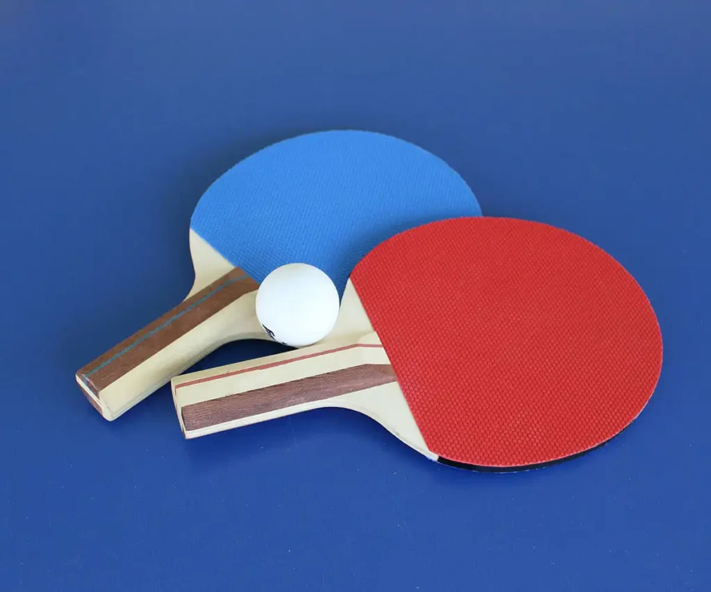 Raquetas de ping-pong con pelota sobre mesa azul
