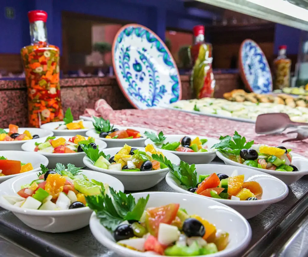 Ensaladas en platos sobre una mesa con aceitunas y verduras, en buffet.