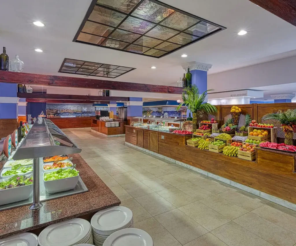 Buffet de frutas y ensaladas en restaurante, con vitrinas y l&aacute;mparas de techo