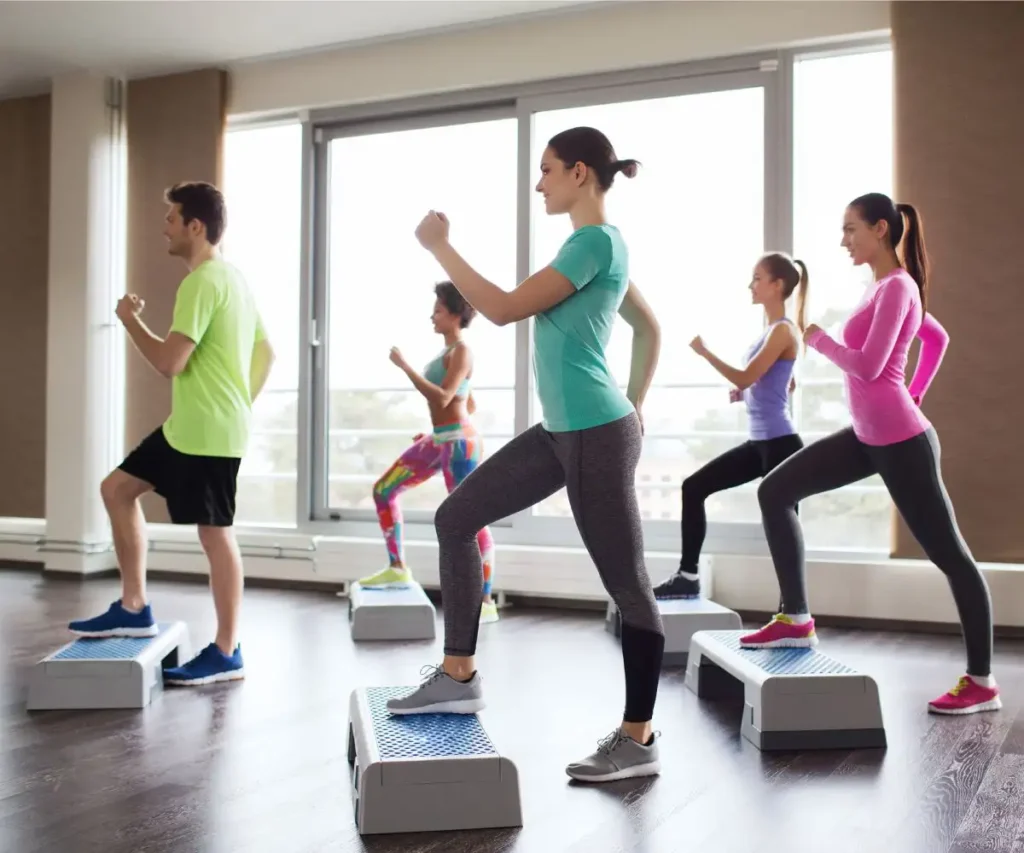 Clase de fitness con varias personas haciendo step en el gimnasio