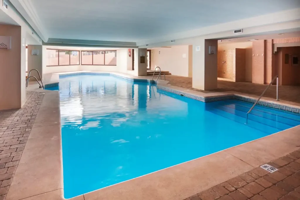Piscina cubierta azul con escalones y &aacute;reas de descanso en un hotel