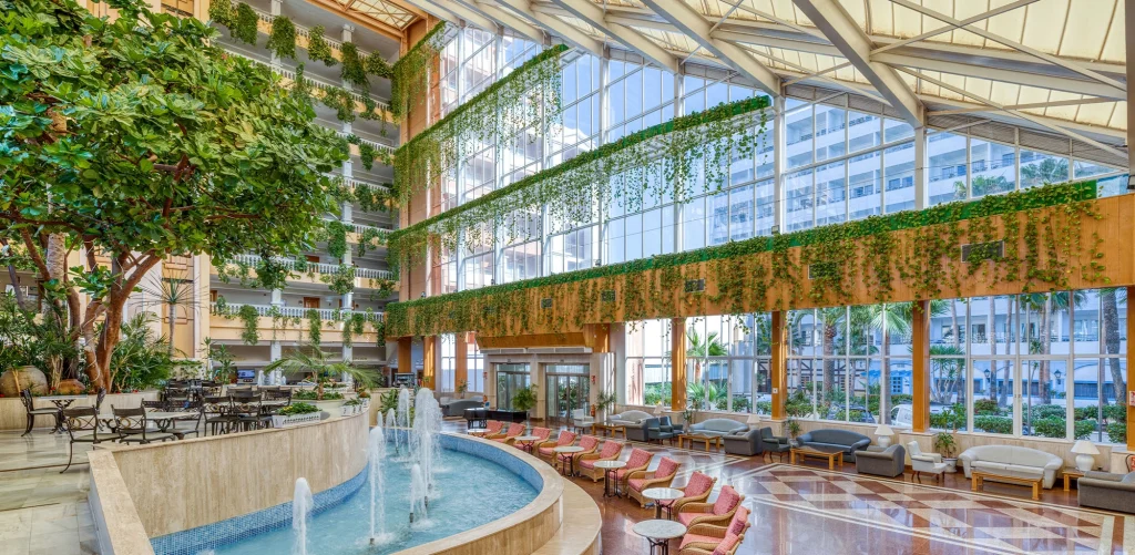 Playacapricho Hotel entrada con fuente, grandes ventanales y enredaderas