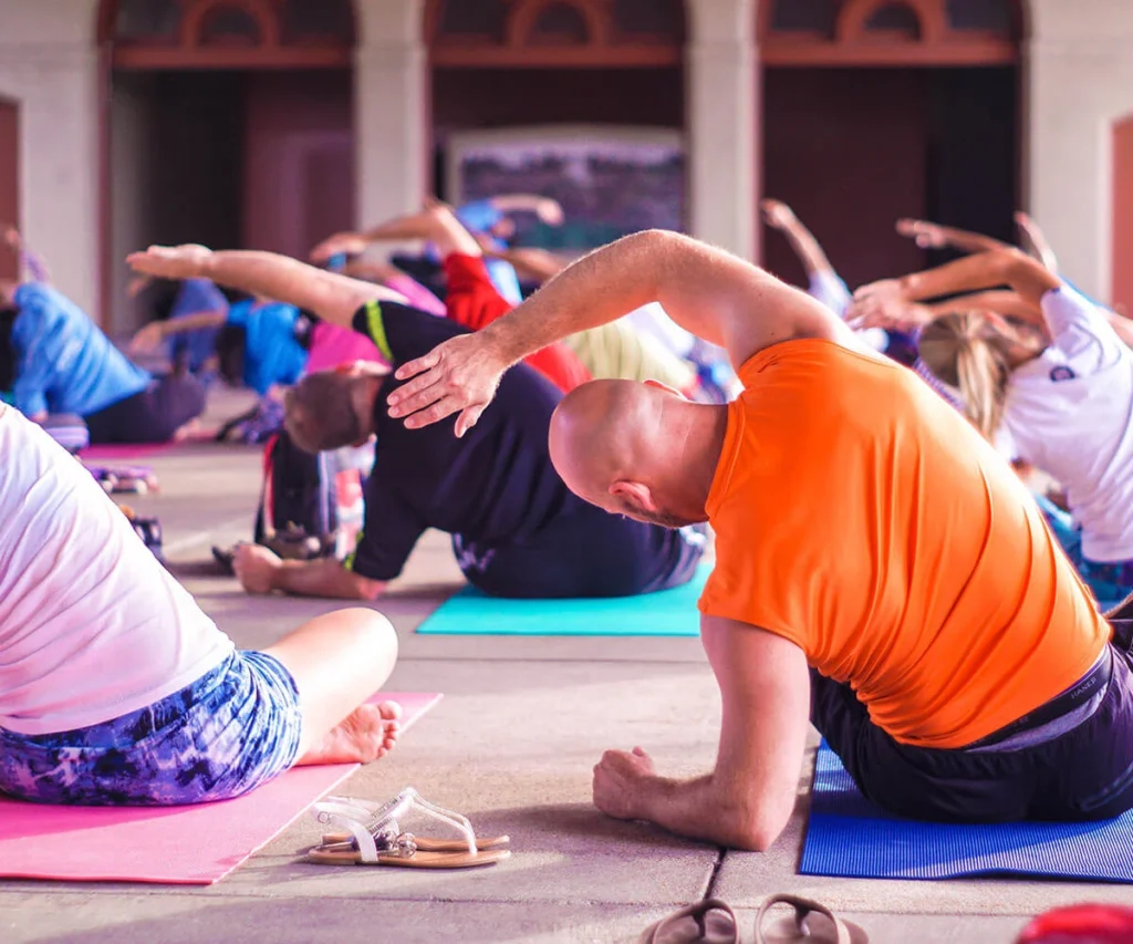 Hombre naranja haciendo plancha en clase de yoga al aire libre