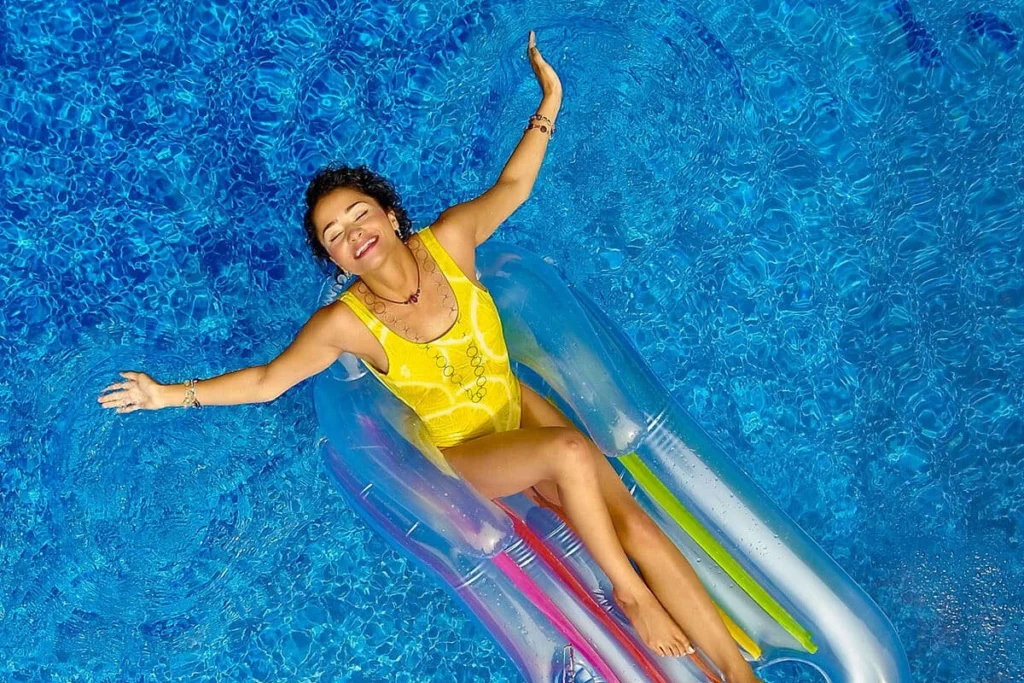 Persona nadando en piscina azul con flotador de rayas multicolor