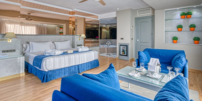 Habitaci&oacute;n moderna con cama grande y muebles azules, decorada con plantas.