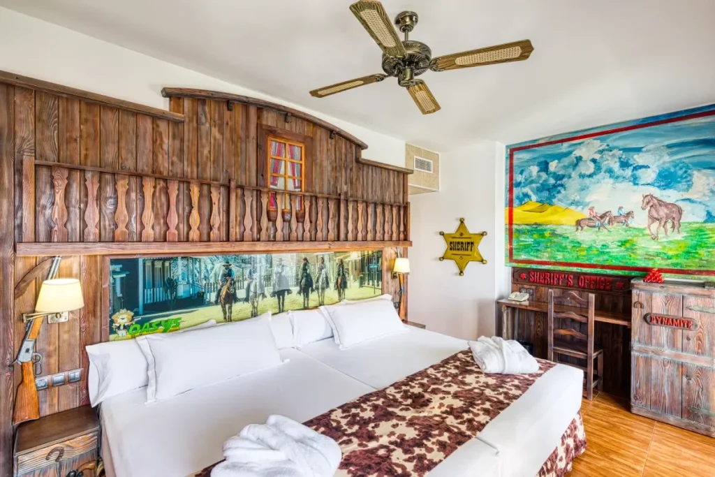 Habitaci&oacute;n con cama doble, ventilador de techo y decoraci&oacute;n de Sheriff en pared