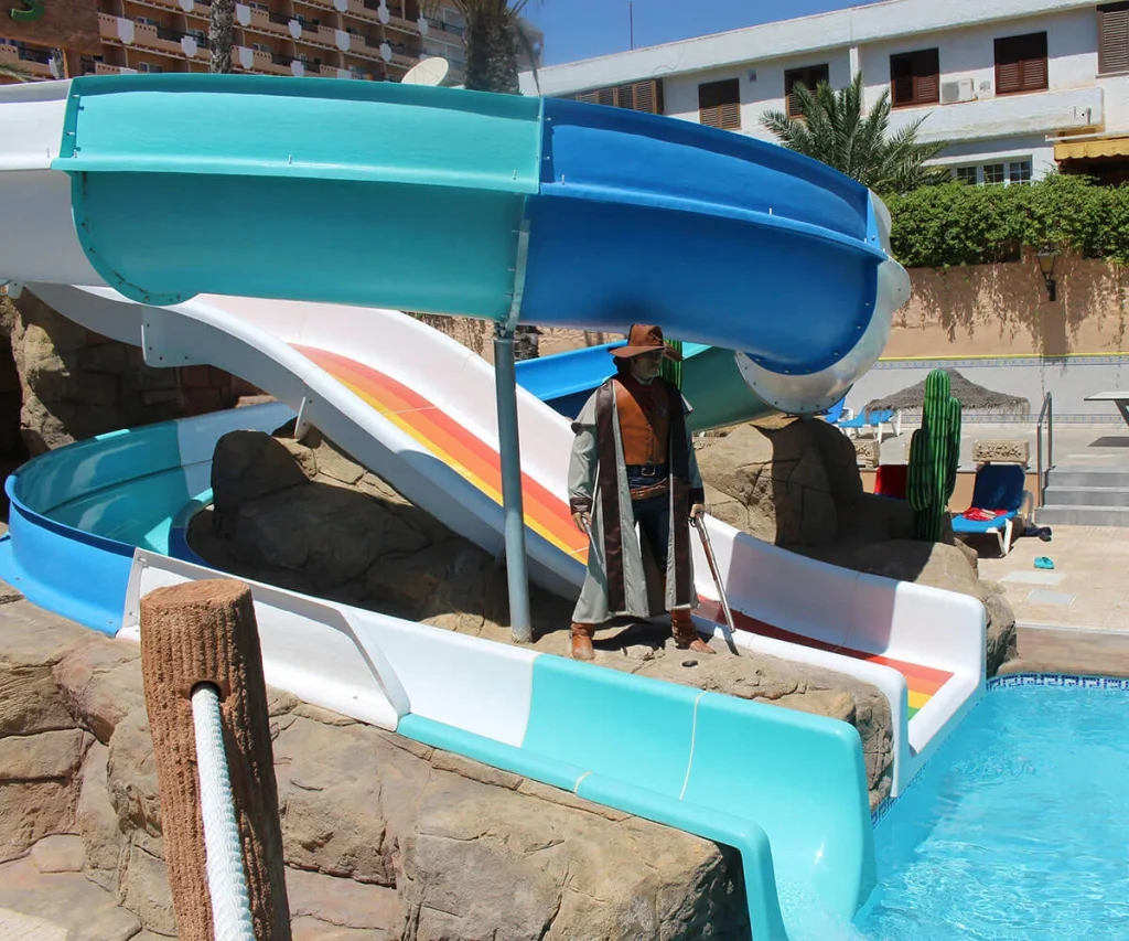 Resbaladera azul y turquesa con un guardia con sombrero junto a la piscina