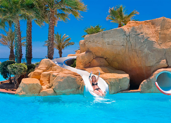 Mujer disfrutando de uno de los toboganes de la piscina de Playaluna Hotel