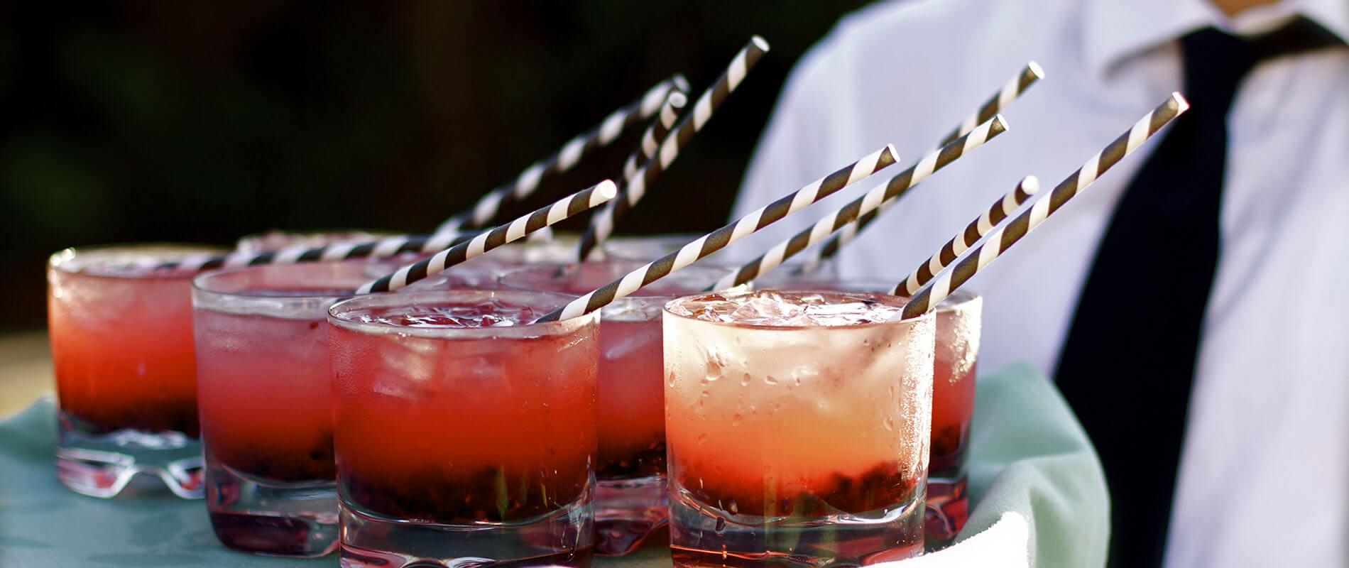 Vasos con c&oacute;cteles rojos y rosados con hielo y pajitas rayadas