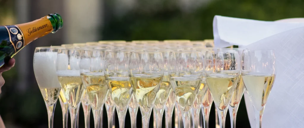 Aperitivo con botella vertiendo en copas de champ&aacute;n al aire libre