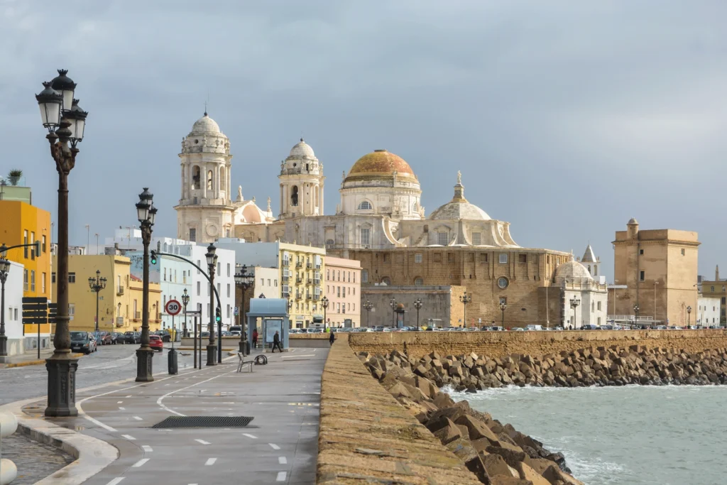Avenida junto al mar con farolas y la catedral de C&aacute;diz al fondo
