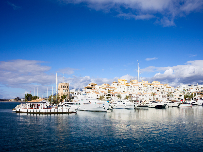 Puerto de Puerto Banús con barcos blancos y el pueblo de fondo. 