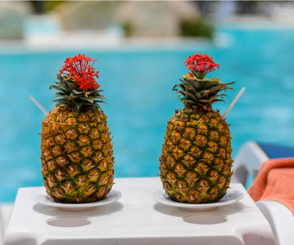 Dos pi&ntilde;as con flores rojas sobre una mesa junto a la piscina