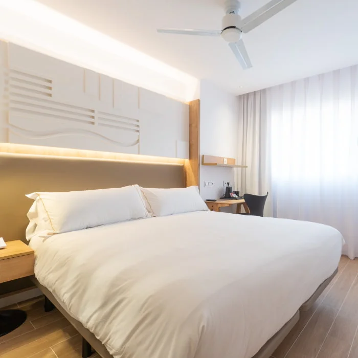 Dormitorio moderno con cama doble y cortinas claras, vista interior.