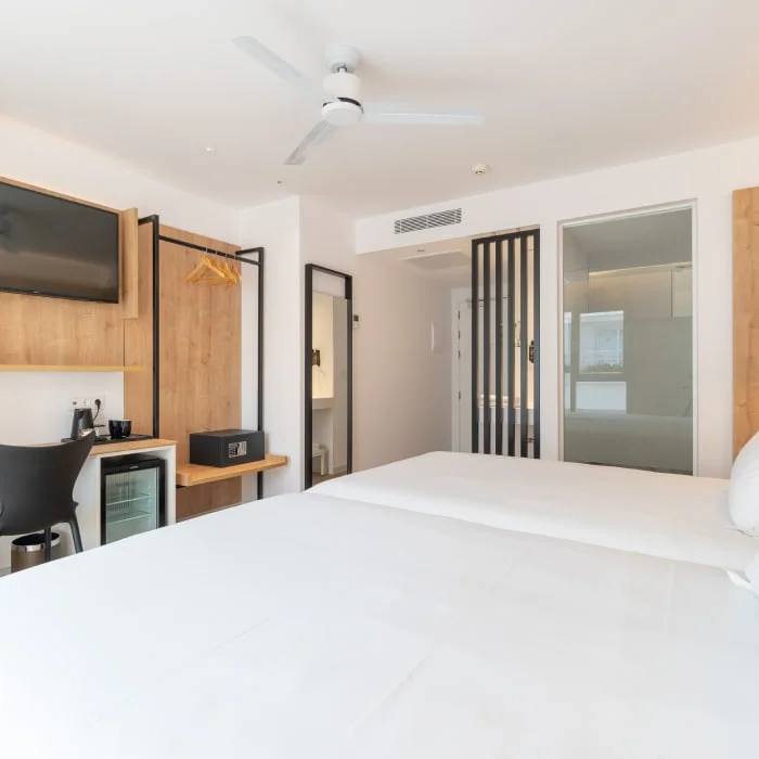 Dormitorio moderno con cama, ventilador y armarios de madera.