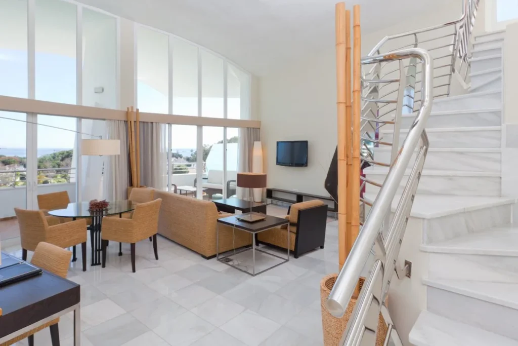 Sala de estar moderna con escalera blanca y vista al mar, terraza interior