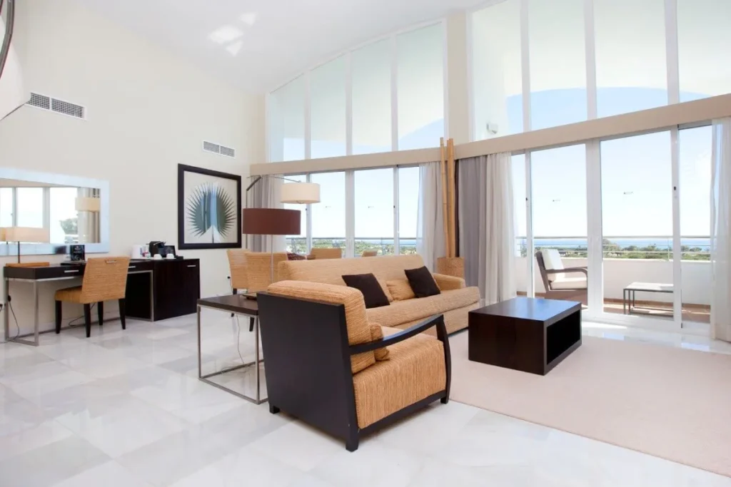 Sala moderna con sof&aacute;, mesa de centro y grandes ventanales al mar