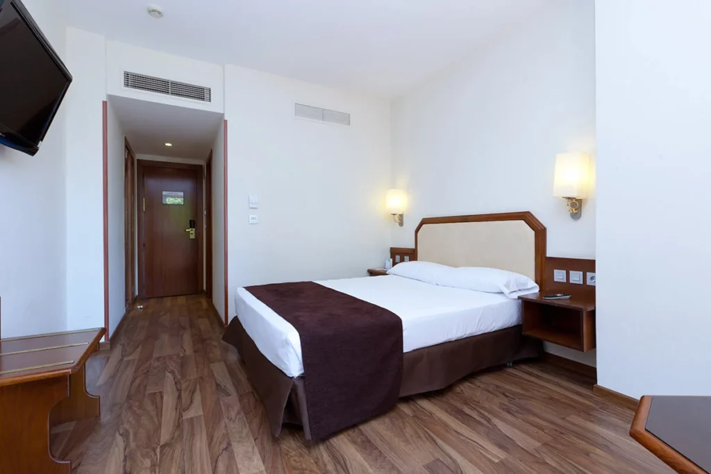 Dormitorio moderno con cama doble, mesilla y paredes blancas.