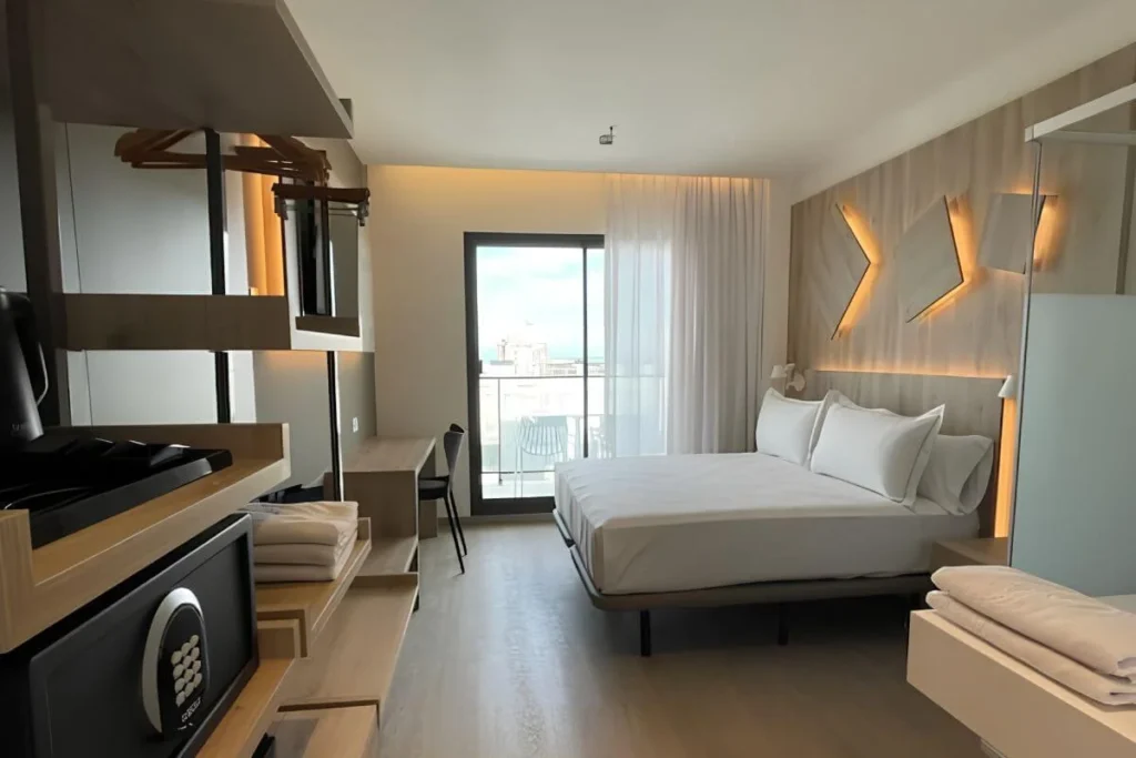 Dormitorio moderno con cama doble, luces c&aacute;lidas y vista exterior por la ventana