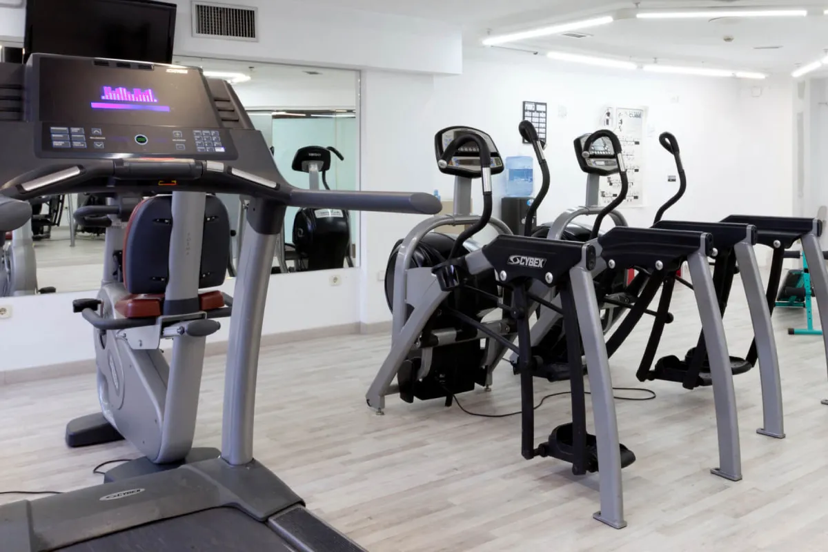 M&aacute;quinas cardiovasculares en gimnasio, con cinta y bicicleta el&iacute;ptica al fondo.