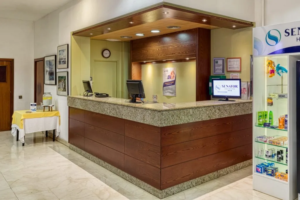 Recepción de hotel con mostrador de madera y vitrinas de productos y folletos
