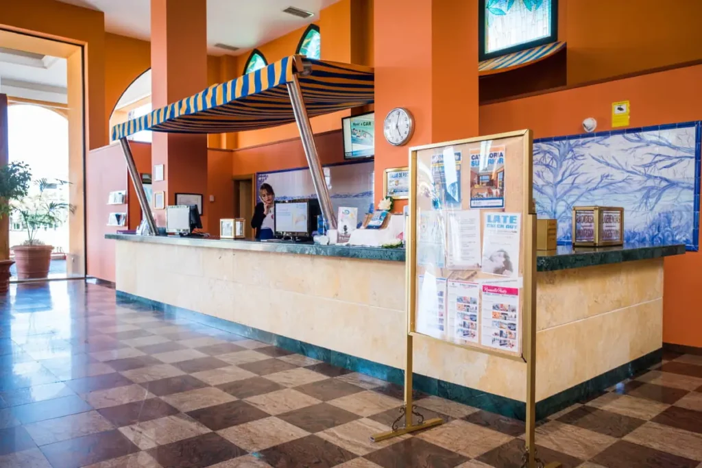 Recepci&oacute;n de hotel con mostrador, pantallas y posters informativos