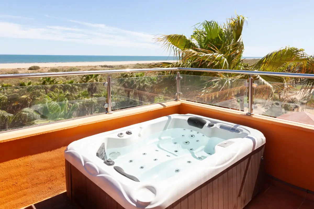 Jacuzzi en terraza con vista al mar y palmeras