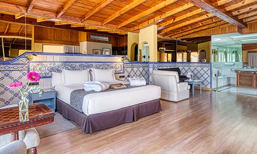 Habitaci&oacute;n de hotel acogedora con cama, sof&aacute; y decoraci&oacute;n de madera y azulejos.