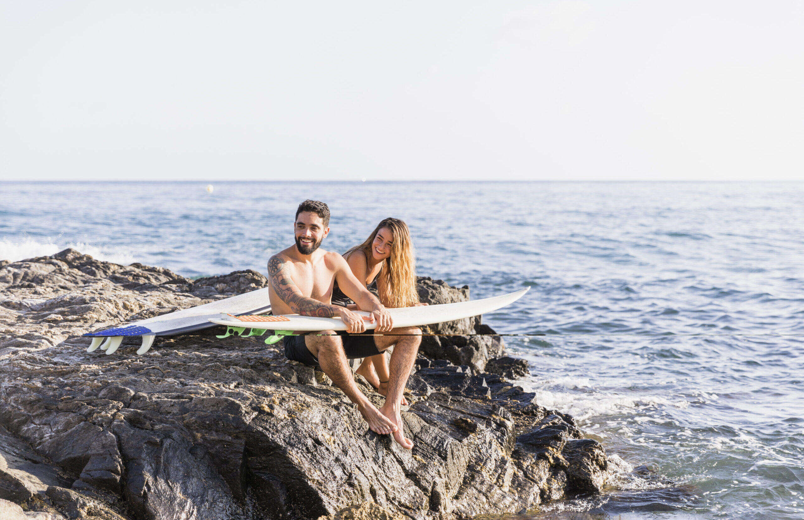 Pareja haciendo Paddle Surf sentados en una roca