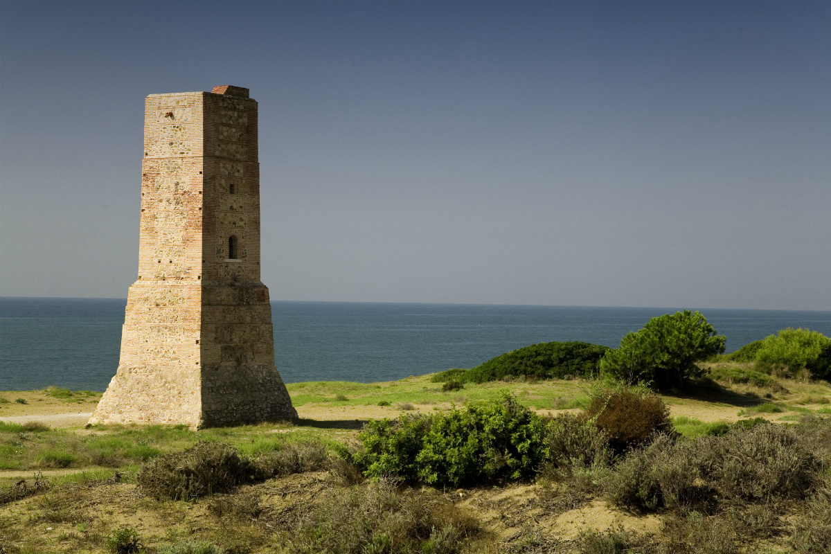 Torre de los ladrones en Marbella con vegetación y mar de fondo.
