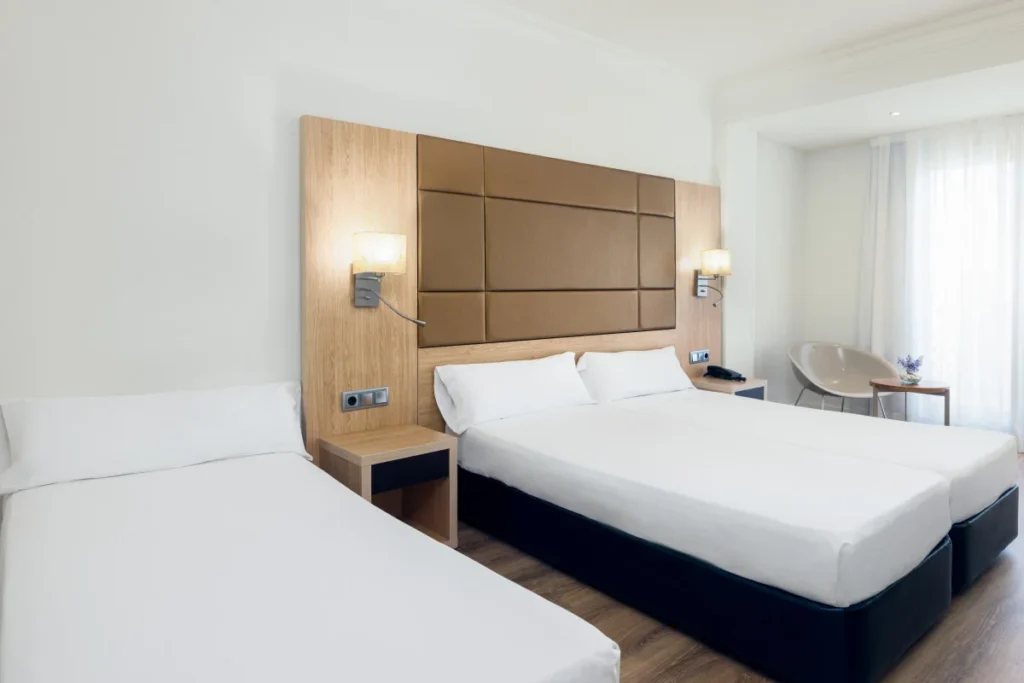 Habitaci&oacute;n hotelera moderna con cama doble y cabecero acolchado marr&oacute;n