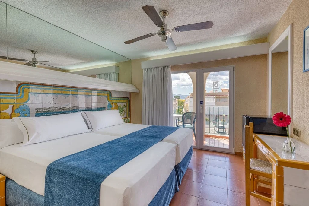 Habitaci&oacute;n de hotel con cama doble, ventilador de techo y balc&oacute;n franc&eacute;s