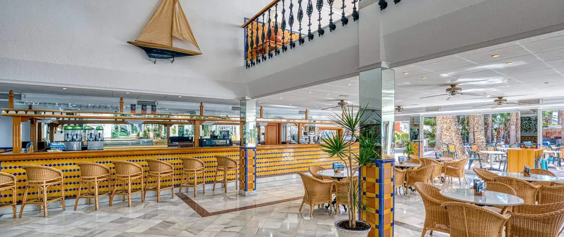 Interior de bar tropical con barra, mesas y sillas de mimbre y l&aacute;mpara decorativa