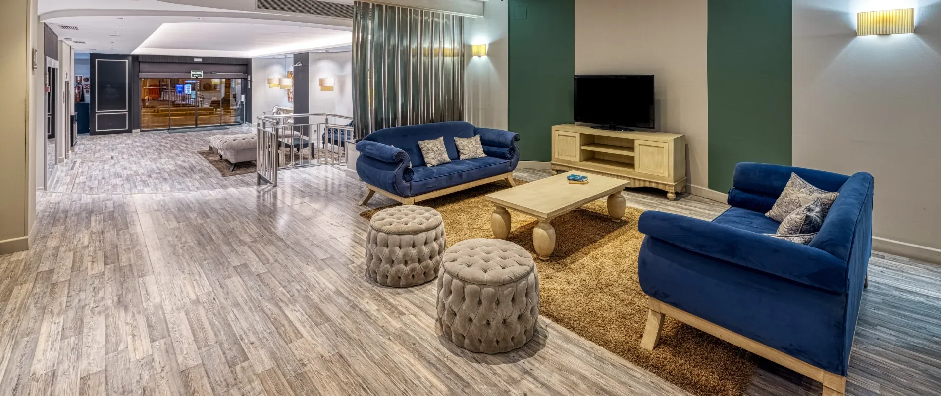 Sala de estar moderna con sof&aacute;s azules, alfombra y TV.