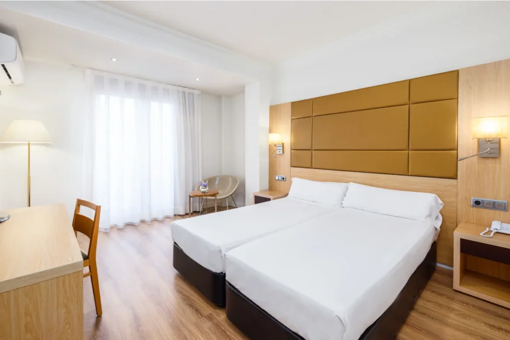 Dormitorio moderno con cama blanca, cabecero dorado y l&aacute;mparas.