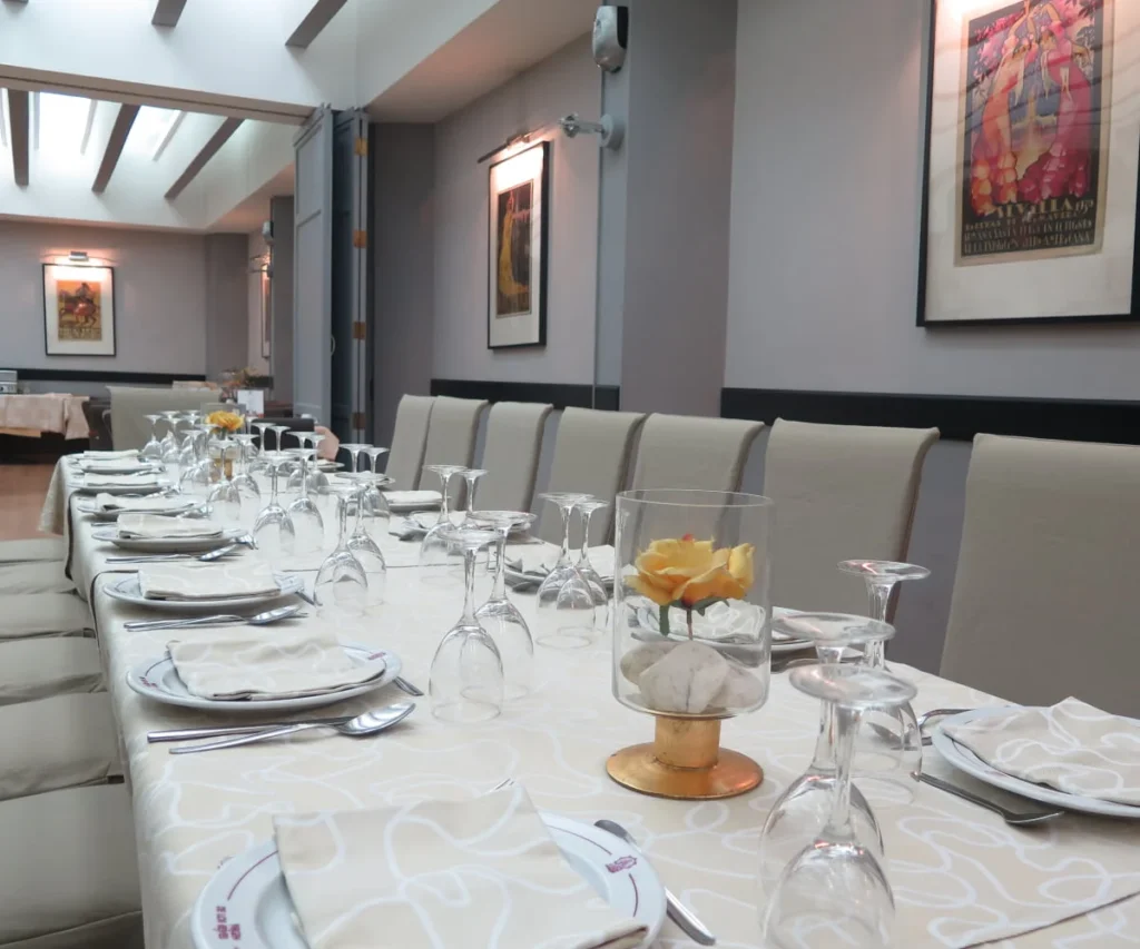 Mesa servida con copas y flores en un comedor elegante con cuadros.