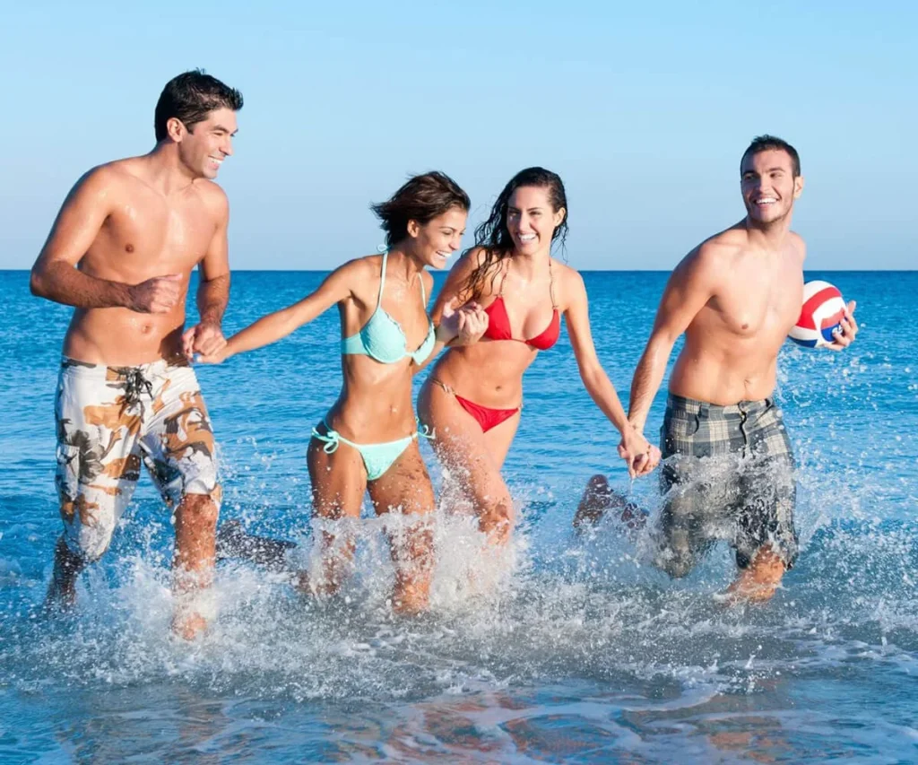 Personas jugando en el mar con trajes de ba&ntilde;o y una pelota inflable.