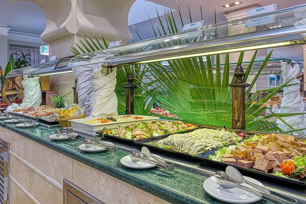 Buffet con alimentos, ensaladas y espadas de verduras en vitrina refrigerada
